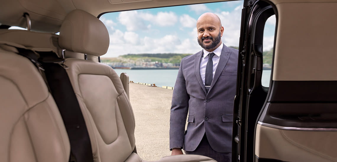 A chauffeur standing beside a car next, as part of Saga's return UK travel service